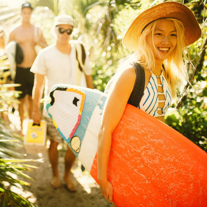 Group of friends enjoying a sunny day, carrying surfboards and sunscreen essentials. Sun Bum,