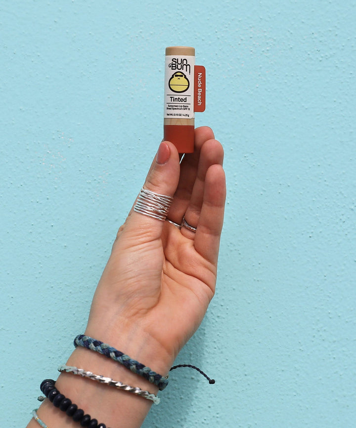 A close-up image of a hand holding a Tinted SPF 15 Lip Balm in 